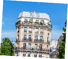 Immeuble haussmannien parisien aux balcons fleuris sous ciel bleu