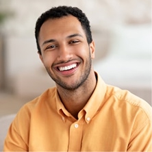 Portrait d'un jeune homme souriant en chemise jaune moutarde