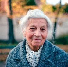 Portrait d'une femme âgée souriante aux cheveux blancs en manteau bleu